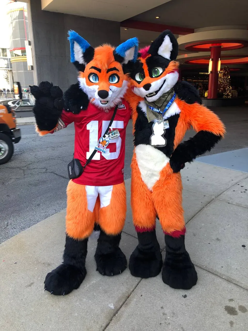 A pair of orange-and-white fursuiters posing together at Midwest FurFest.